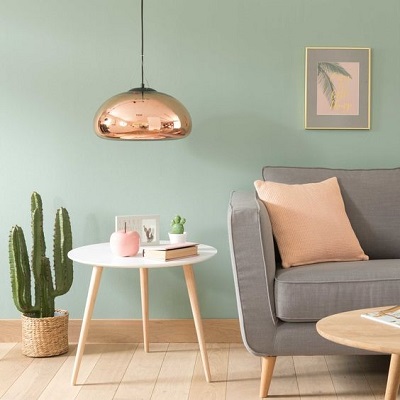 Design interior cu perete verde menta, canapea gri si lampa arama