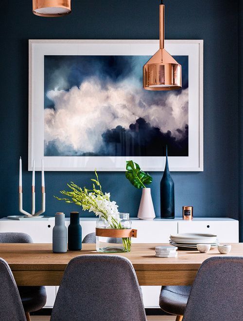 Loc de luat masa cu perete albastru si tablou abstract nori